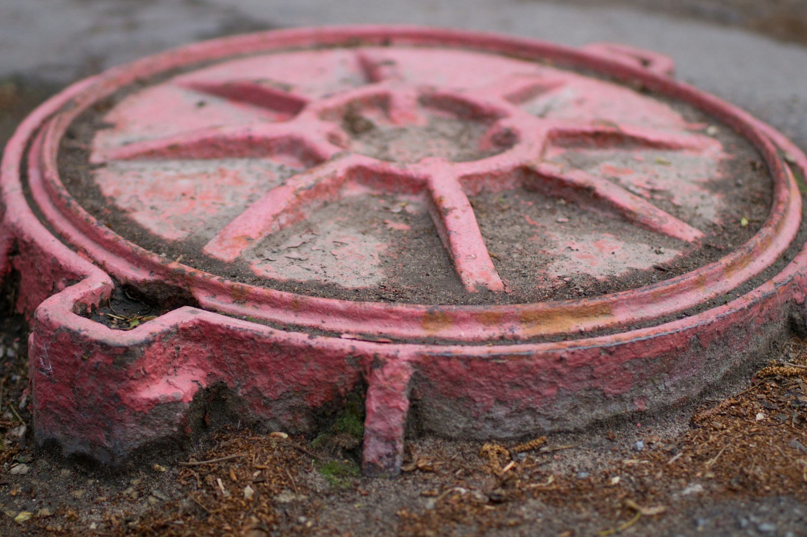 A red manhole cover rests on the ground.