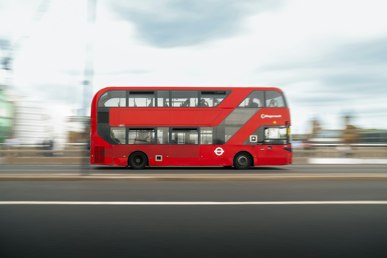 A red double decker bus driving down a street